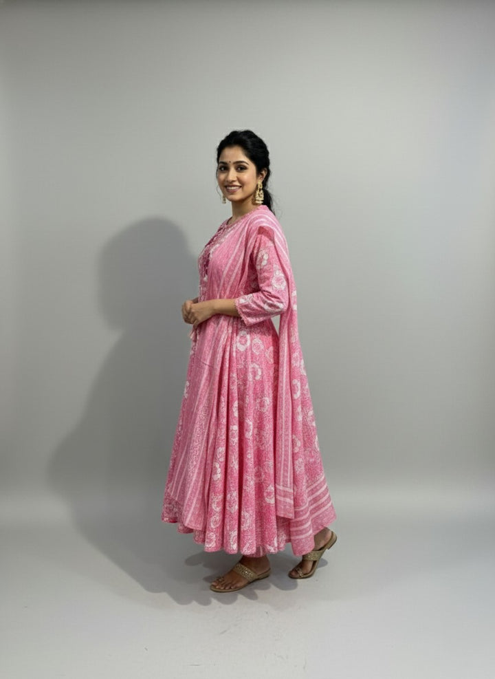 Woman wearing a pink traditional outfit with white patterns on a plain background