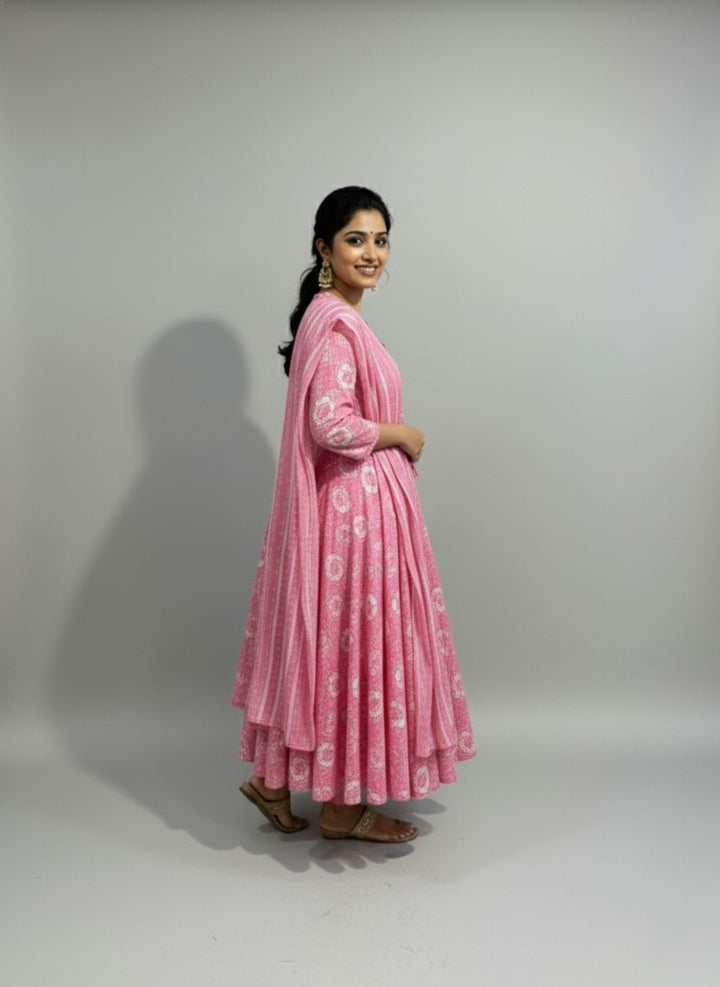 Woman wearing a pink traditional outfit with a white pattern on a plain background
