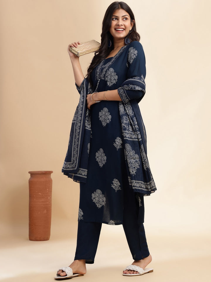 Woman wearing a navy blue kurta with white patterns, standing against a beige background.