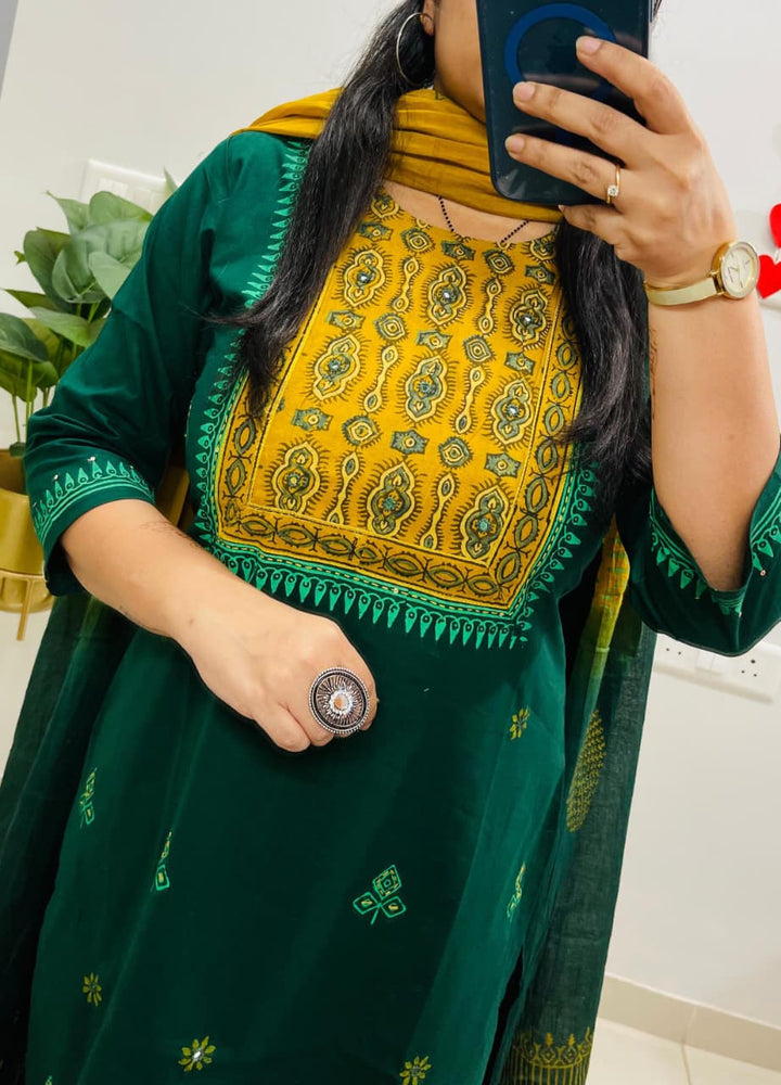 Person wearing a green and yellow traditional outfit with intricate patterns.