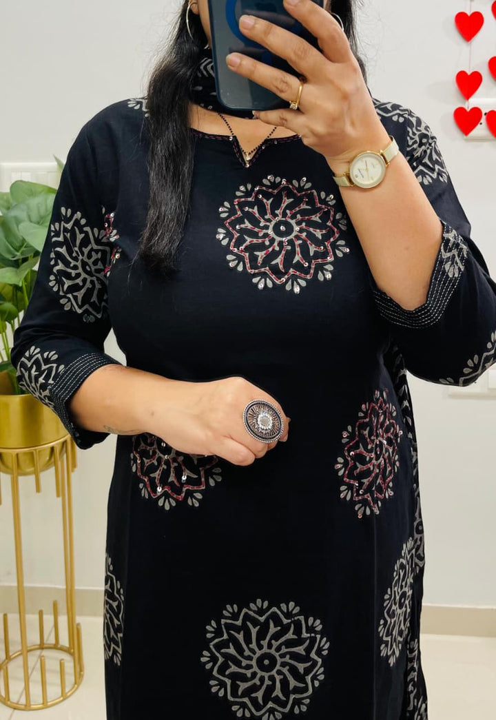 A person wearing a black dress with white patterns.