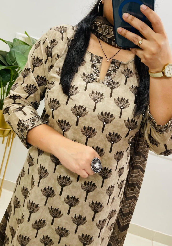 Woman wearing a beige kurta with black floral patterns, holding a phone.