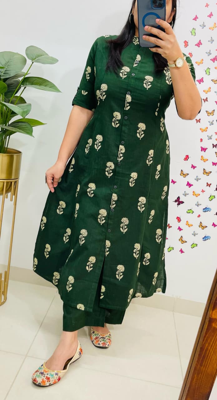 Person wearing a green dress with skull pattern in front of a colorful butterfly wall.