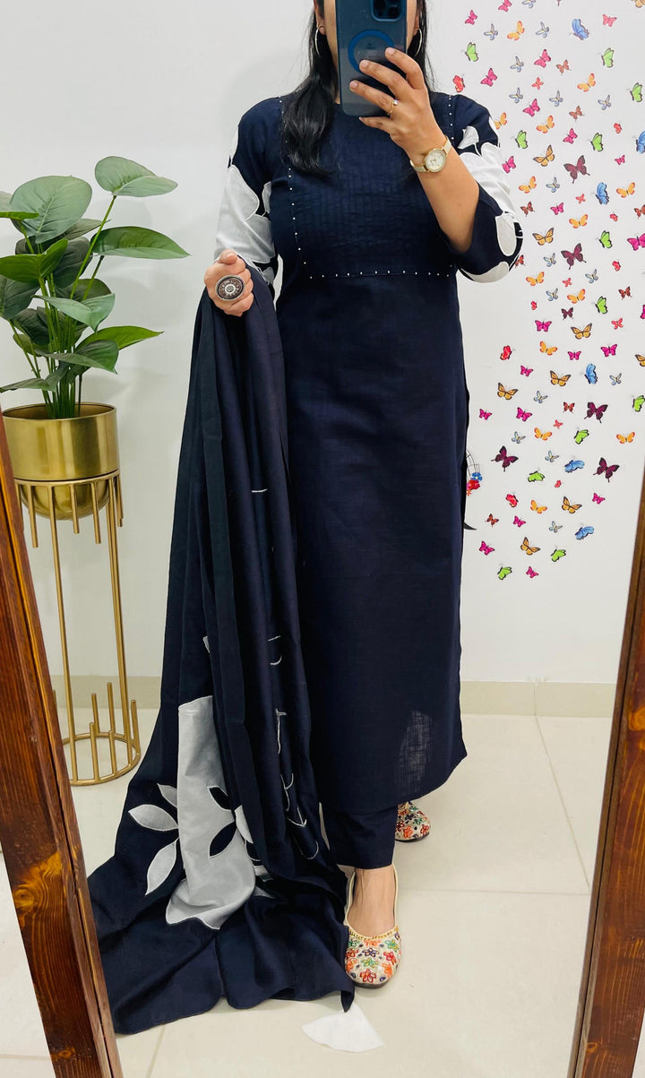 Person wearing a navy blue dress with floral details, standing in front of a mirror.