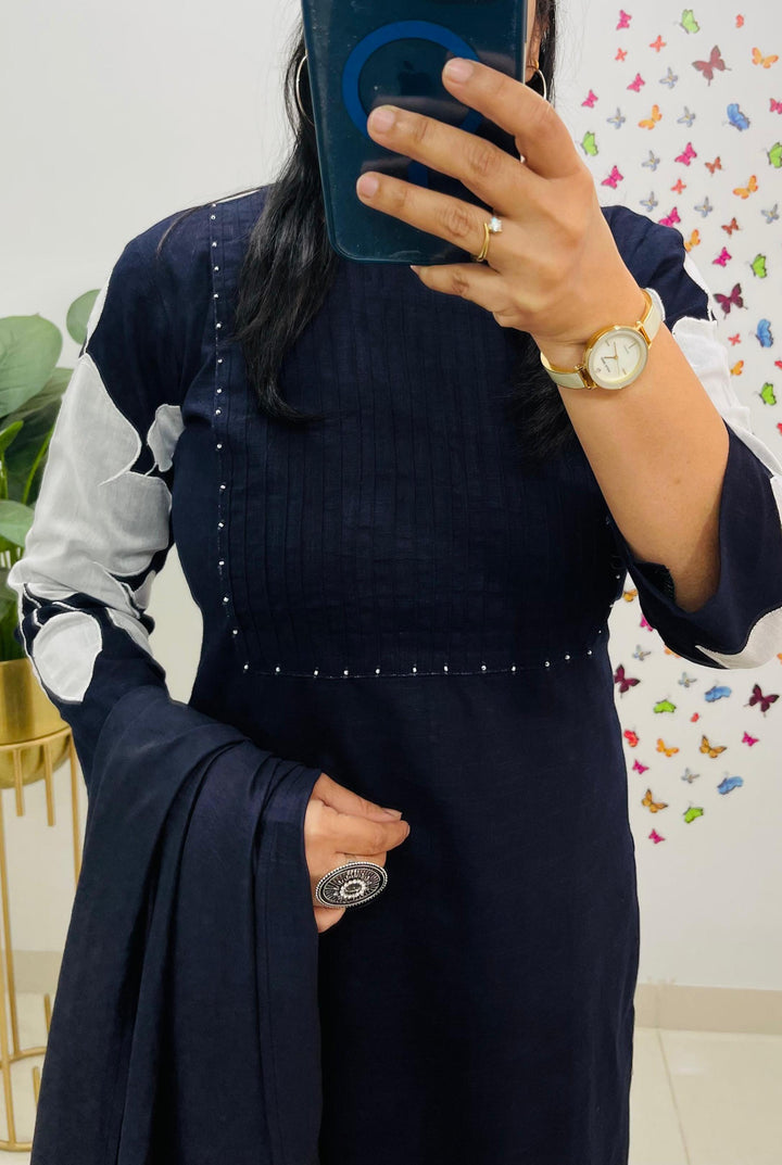 Person wearing a navy blue outfit with white patterns, holding a phone.