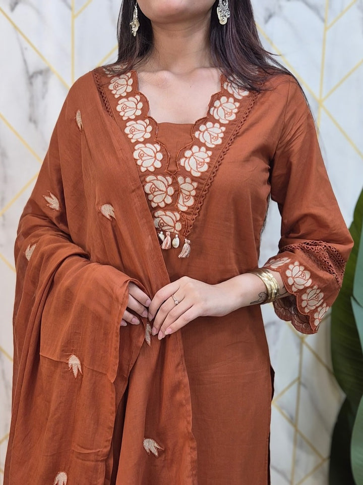 Brown traditional outfit with floral embroidery against a marble wall background