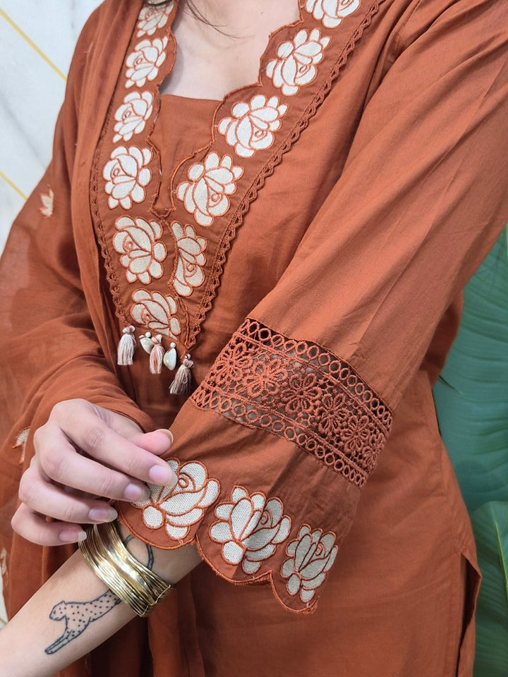 Brown embroidered garment with intricate designs and a gold bracelet.